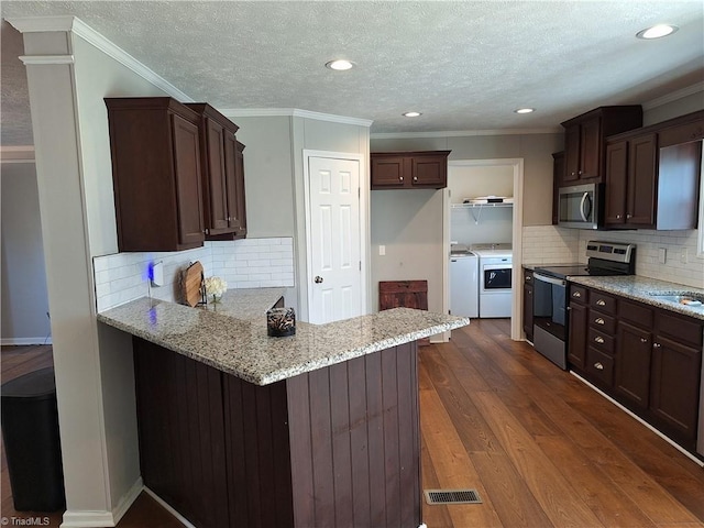 kitchen featuring visible vents, appliances with stainless steel finishes, dark wood-type flooring, a peninsula, and washing machine and dryer