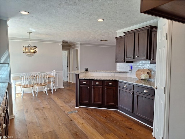 kitchen with light wood-style floors, crown molding, a peninsula, and dark brown cabinets