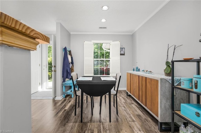 dining area with wood finished floors, baseboards, crown molding, and recessed lighting