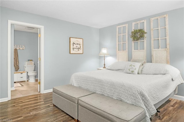 bedroom with wood finished floors, baseboards, and connected bathroom