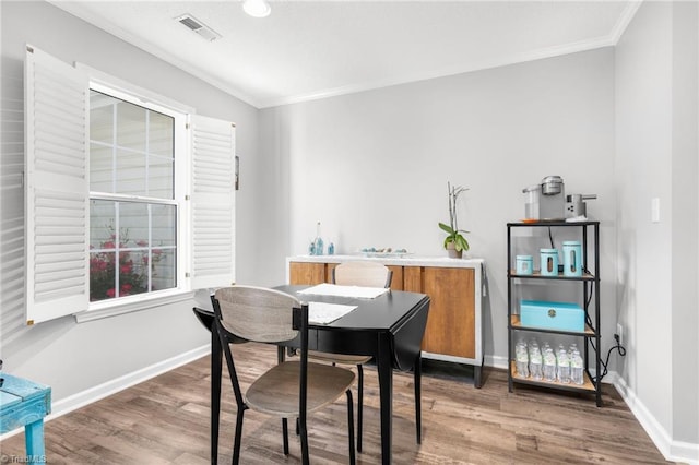 dining space featuring crown molding, wood finished floors, and baseboards