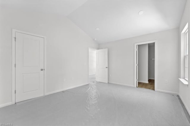 2154 E First St, Winston-Salem, NC 27101 - unfurnished bedroom with vaulted ceiling, a spacious closet, baseboards, and carpet floors