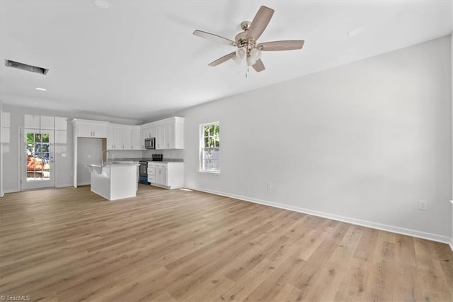 2154 E First St, Winston-Salem, NC 27101 - unfurnished living room featuring light wood-style floors, baseboards, a ceiling fan, and a sink
