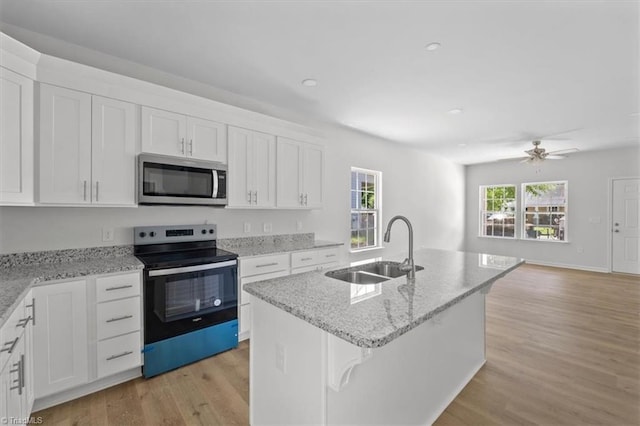 2154 E First St, Winston-Salem, NC 27101 - kitchen featuring appliances with stainless steel finishes, a sink, light wood finished floors, open floor plan, and white cabinets