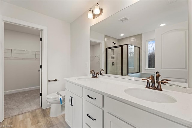 5756 Siler St, Trinity, NC 27370 - bathroom featuring double vanity, a spacious closet, a shower stall, and wood finished floors