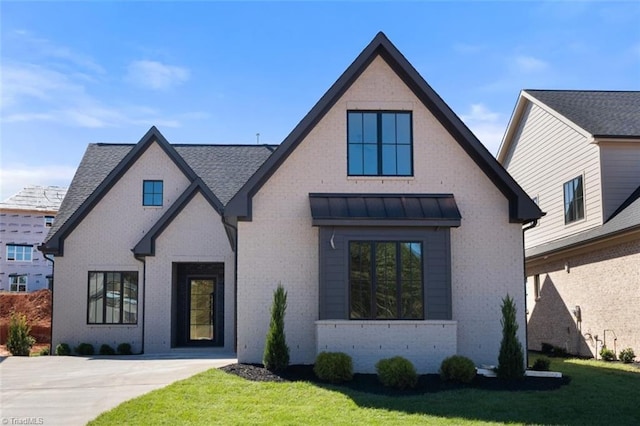 view of front of home featuring brick siding, metal roof, a standing seam roof, and a front yard