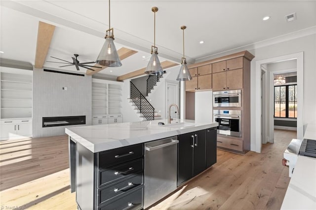 kitchen with beam ceiling, dark cabinets, appliances with stainless steel finishes, and a sink