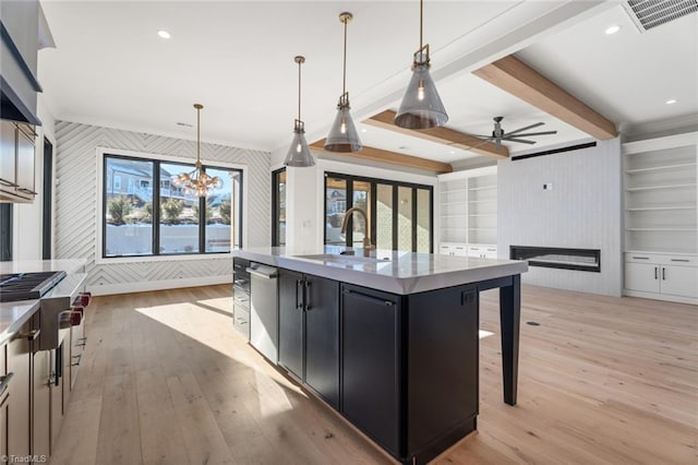 kitchen with dark cabinetry, visible vents, a fireplace, a sink, and light wood-style floors