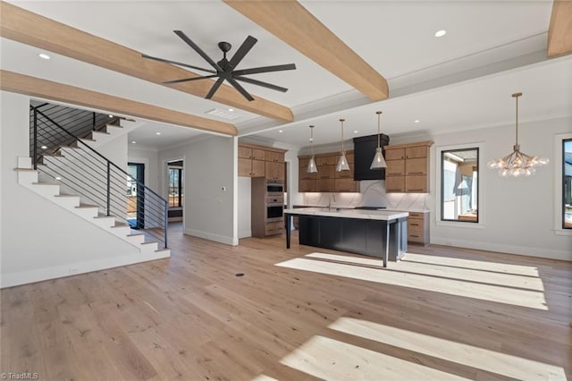 kitchen with light wood finished floors, beam ceiling, open floor plan, and light countertops