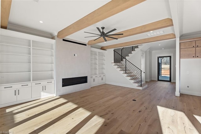 unfurnished living room with stairway, visible vents, beam ceiling, light wood-style flooring, and a fireplace