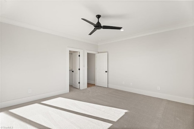 unfurnished bedroom with a walk in closet, ornamental molding, carpet floors, baseboards, and ceiling fan