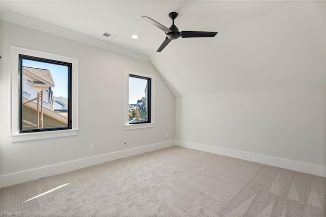 additional living space with visible vents, light colored carpet, lofted ceiling, and baseboards