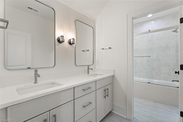 bathroom with double vanity, visible vents, bath / shower combo with glass door, and a sink