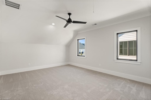 additional living space featuring lofted ceiling, baseboards, visible vents, and light carpet