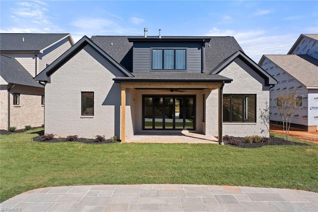 rear view of house with brick siding, a patio, a ceiling fan, and a yard