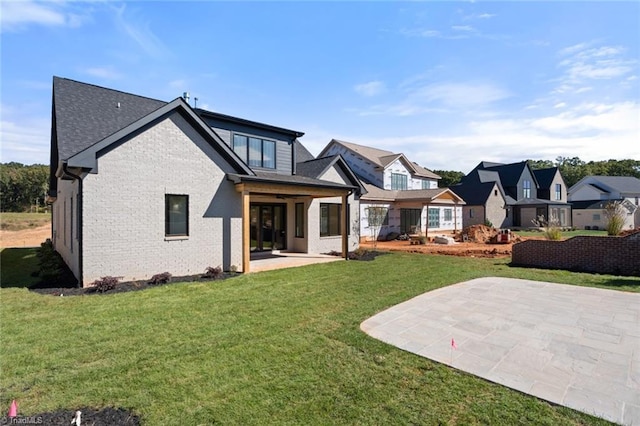 back of house featuring a yard, a patio, and brick siding