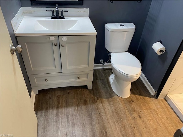 bathroom featuring baseboards, vanity, toilet, and wood finished floors