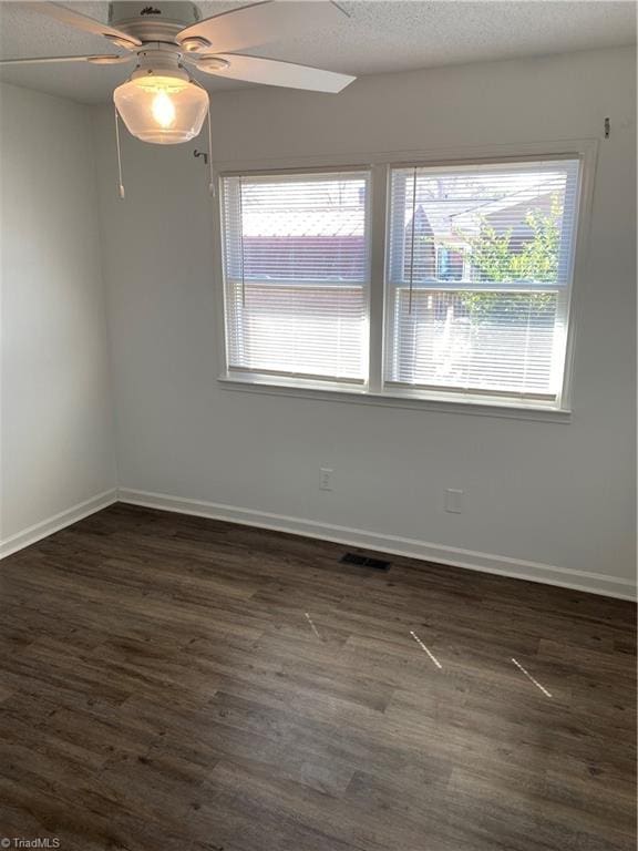 spare room with dark wood finished floors, a textured ceiling, baseboards, and ceiling fan