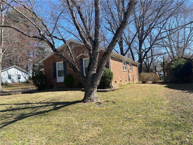 view of home's exterior with crawl space, a yard, and brick siding