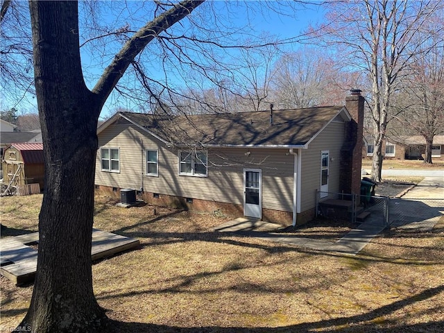 rear view of property with central AC, fence, crawl space, a lawn, and a chimney