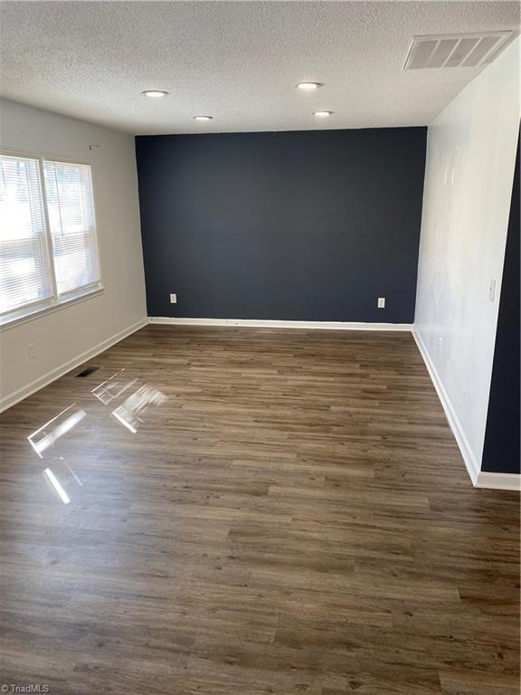 spare room with baseboards, visible vents, and dark wood-type flooring