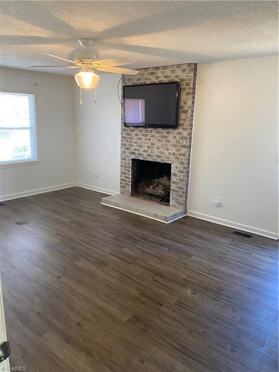 unfurnished living room with a textured ceiling, dark wood-style flooring, a fireplace, and baseboards