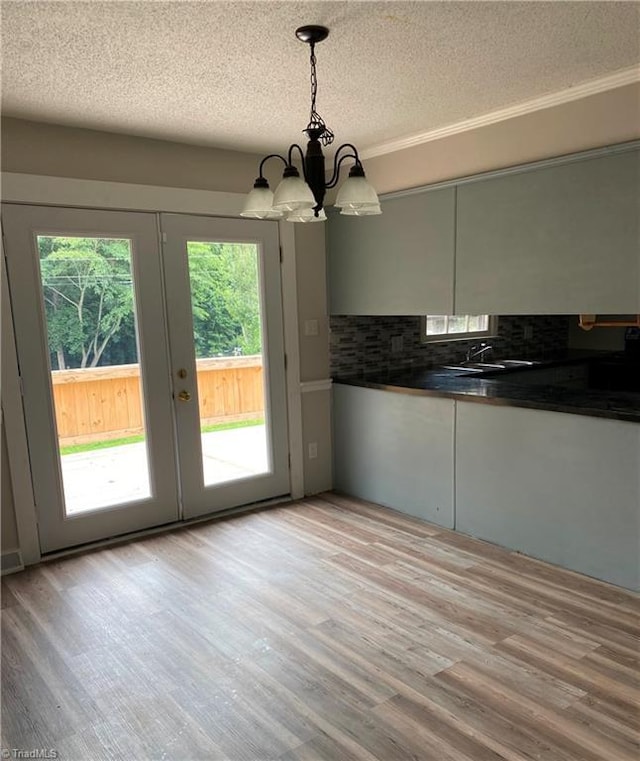 kitchen with pendant lighting, sink, light hardwood / wood-style flooring, tasteful backsplash, and a textured ceiling