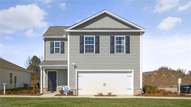 view of front of property featuring a front lawn, central AC, and a garage