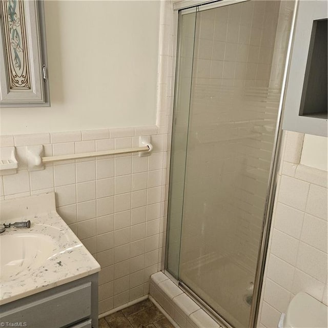 bathroom with vanity, tile patterned floors, toilet, tile walls, and a shower with shower door