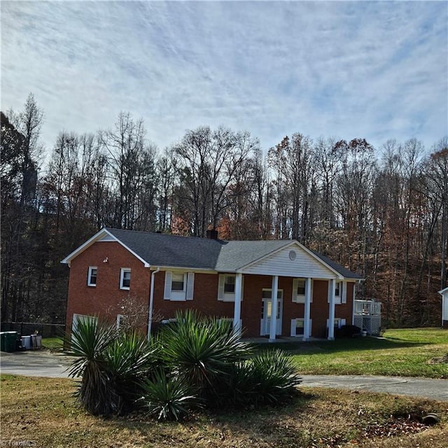 view of front of home featuring central AC unit, covered porch, and a front yard