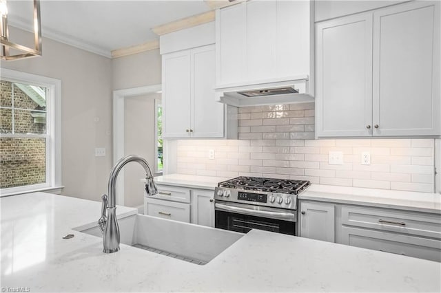 kitchen with sink, crown molding, stainless steel range with gas stovetop, light stone countertops, and white cabinets