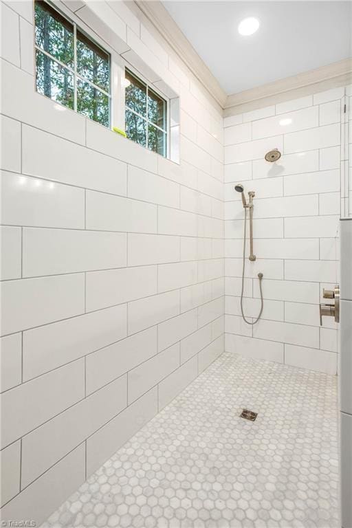 bathroom with a tile shower and ornamental molding