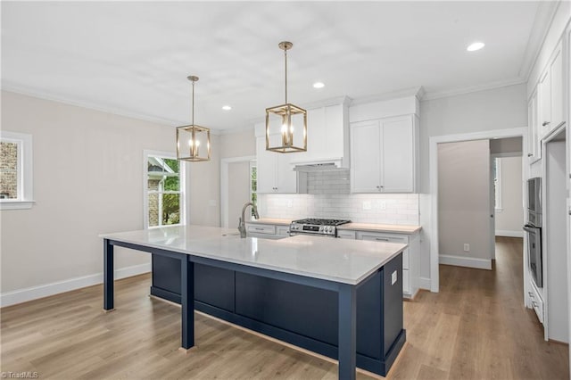 kitchen featuring sink, white cabinetry, appliances with stainless steel finishes, pendant lighting, and a kitchen island with sink