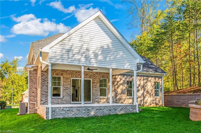 rear view of house with central AC, ceiling fan, and a lawn