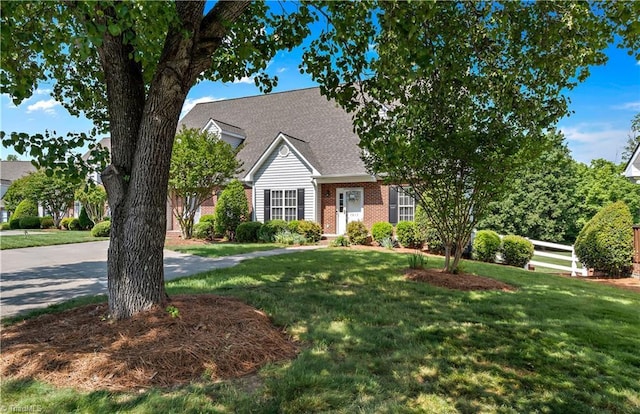 view of front of property with brick siding, roof with shingles, and a front lawn