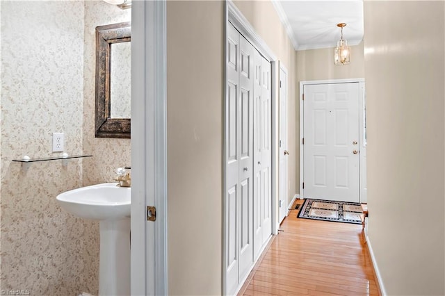 corridor featuring baseboards, ornamental molding, wood finished floors, and a chandelier