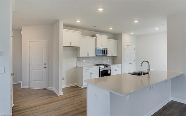 kitchen featuring dark wood-type flooring, a sink, white cabinets, appliances with stainless steel finishes, and decorative backsplash