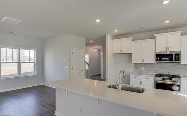 kitchen featuring appliances with stainless steel finishes, white cabinets, a sink, and tasteful backsplash