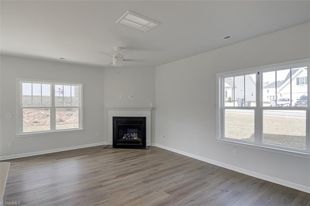 unfurnished living room featuring visible vents, a fireplace with flush hearth, ceiling fan, wood finished floors, and baseboards