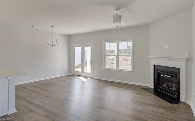 unfurnished living room with a ceiling fan, a glass covered fireplace, baseboards, and wood finished floors