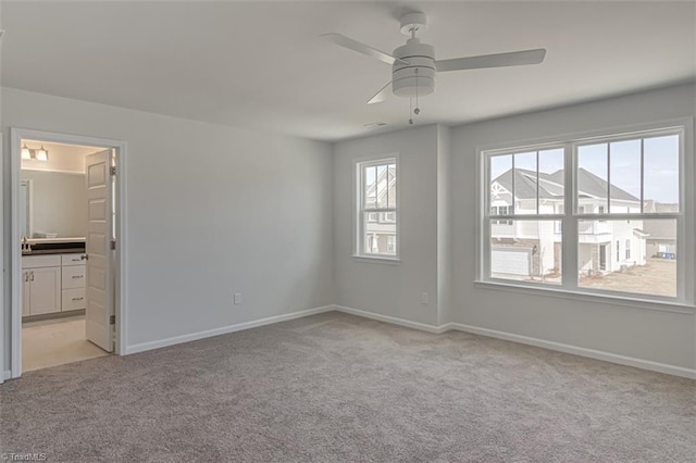 unfurnished bedroom featuring a ceiling fan, light carpet, ensuite bath, and baseboards