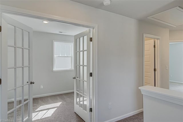 hallway featuring attic access, carpet, and baseboards