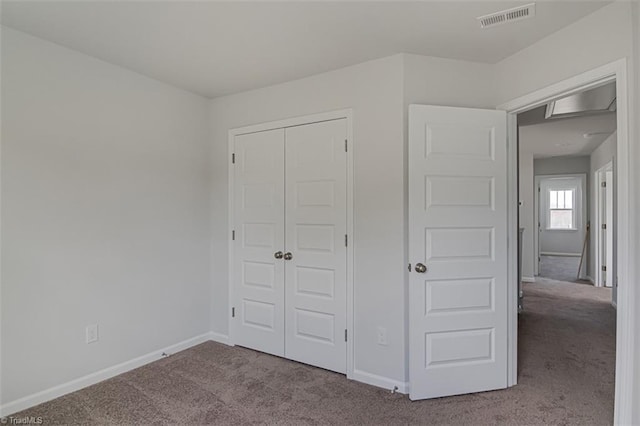 unfurnished bedroom with carpet floors, baseboards, visible vents, and a closet