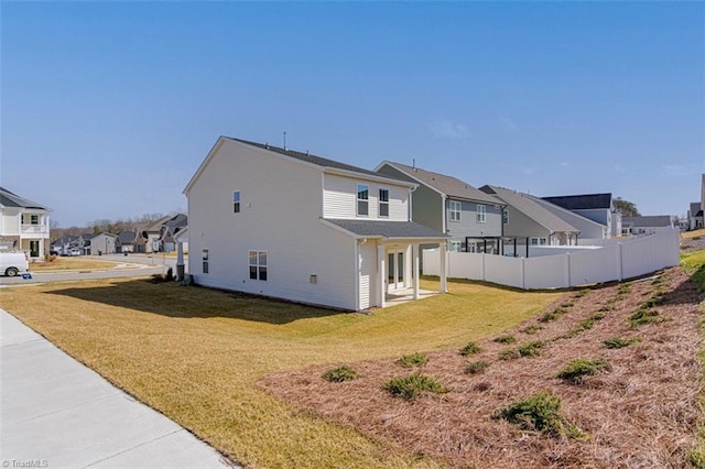 back of house featuring a yard, fence, and a residential view