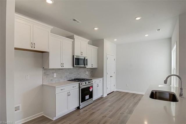 kitchen with tasteful backsplash, visible vents, stainless steel appliances, light countertops, and a sink