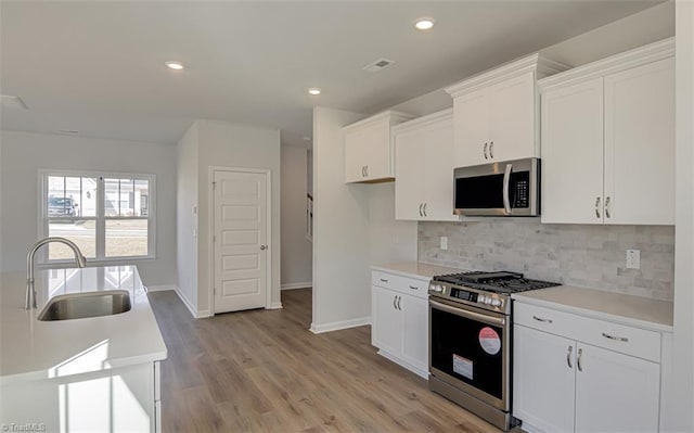 kitchen with decorative backsplash, stainless steel appliances, a sink, and light countertops