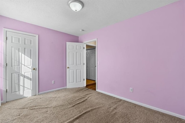 unfurnished bedroom with carpet floors, a textured ceiling, and baseboards