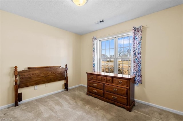 bedroom with light carpet, visible vents, baseboards, and a textured ceiling