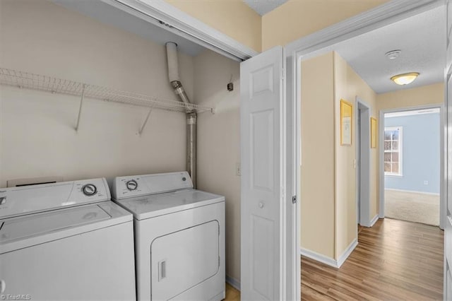 clothes washing area with laundry area, separate washer and dryer, light wood-type flooring, and baseboards