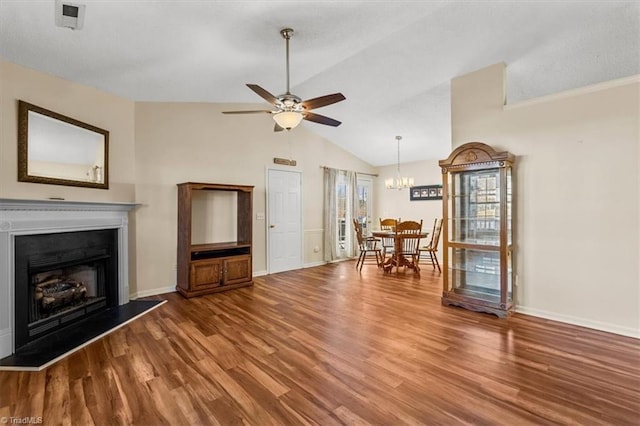 unfurnished living room featuring a fireplace with raised hearth, ceiling fan with notable chandelier, wood finished floors, baseboards, and vaulted ceiling